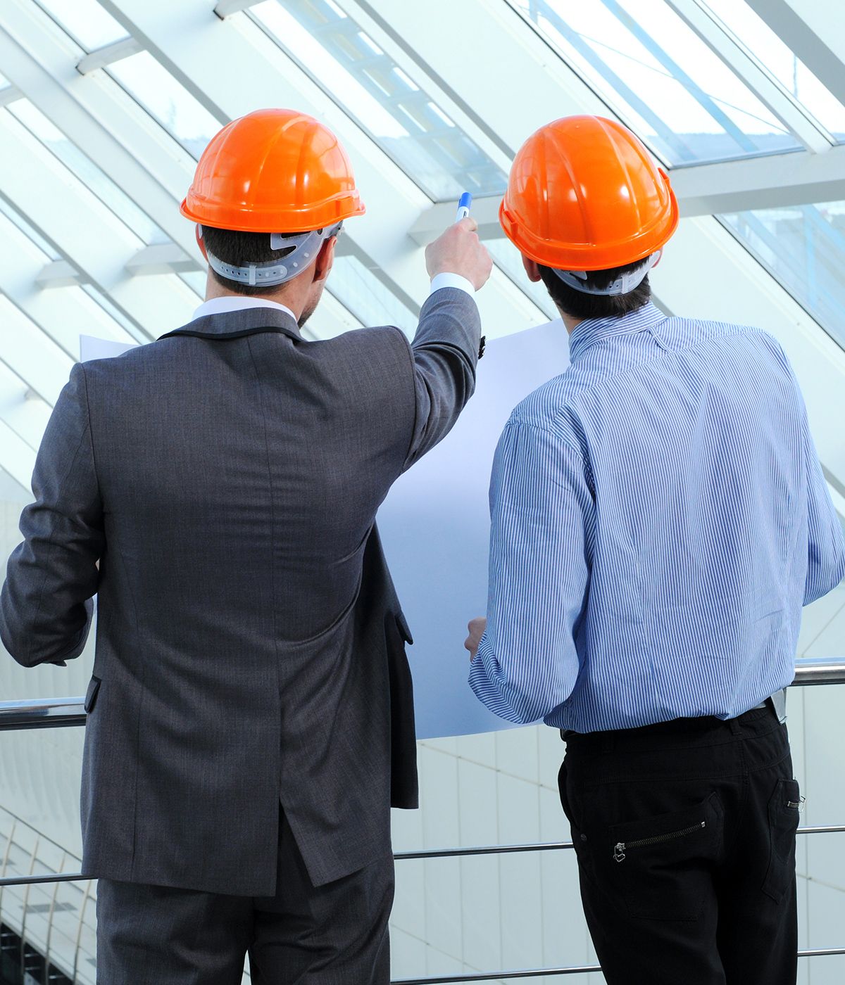 Zwei Männer mit Schutzhelmen betrachten Fenster in einem Gebäude